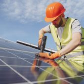 Male worker with solar batteries. Man in a protective helmet. Installing stand-alone solar panel system.